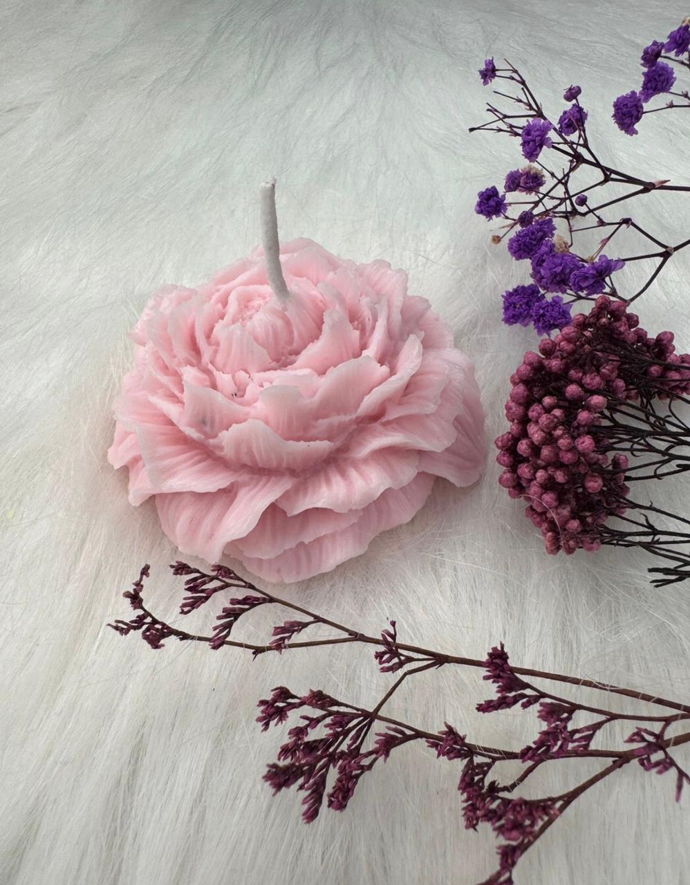 Blush pink peony shaped decorative candle with floral styling on soft textured background